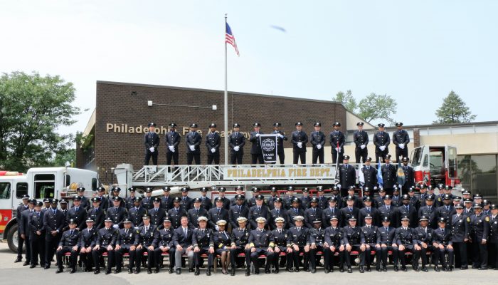 Firefighters in dress uniforms pose for formal class portrait