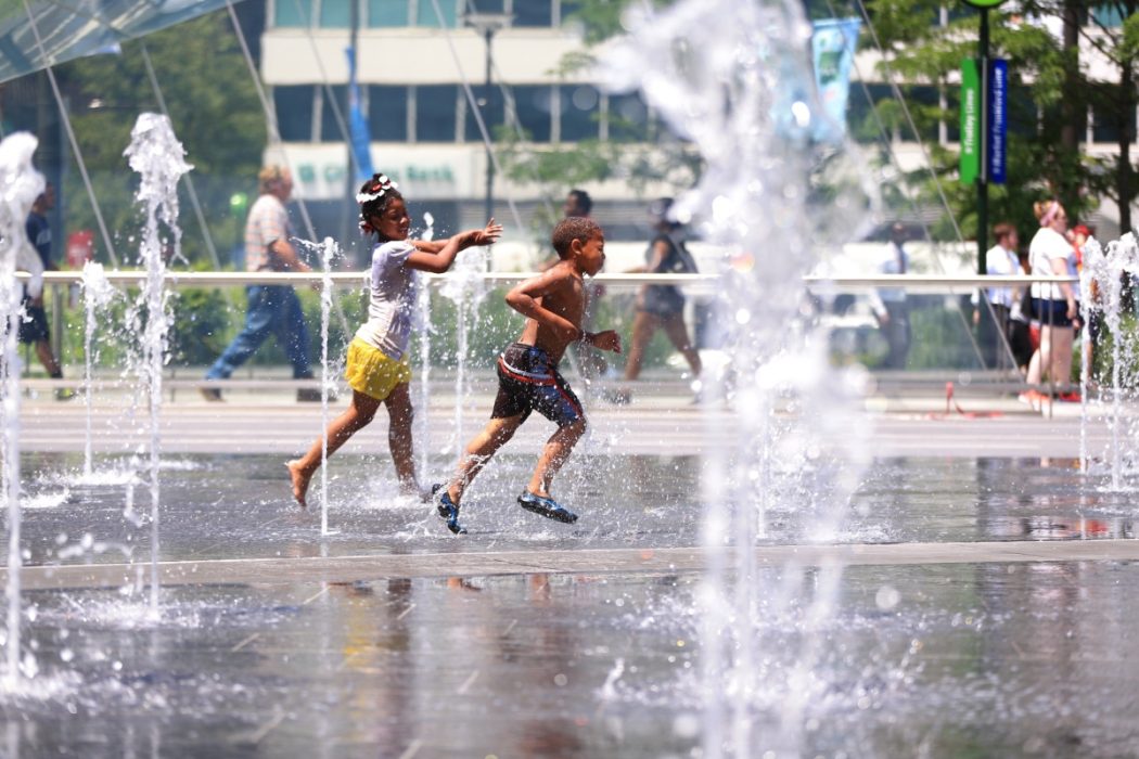 Two children run through the water at the Dilworth Park sprayground