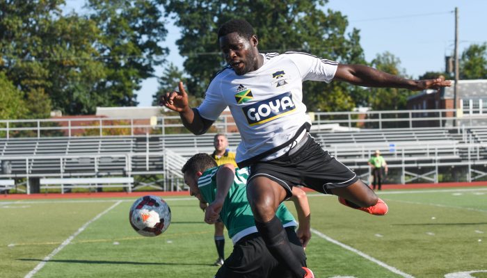 A player from team Jamaica in the air, above the soccer ball