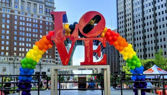 LOVE statue with rainbow balloon arch in the background.