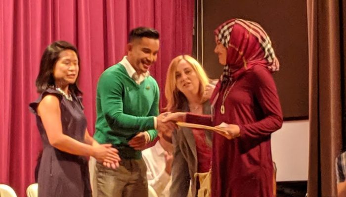 Several people on stage taking part in a naturalization ceremony for U.S. Citizenship.