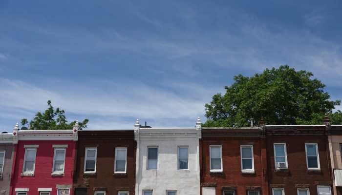A clear sky and a row of two-story, brick rowhomes each structured the same but with their own unique touches showing the diversity of Philly rowhomes.