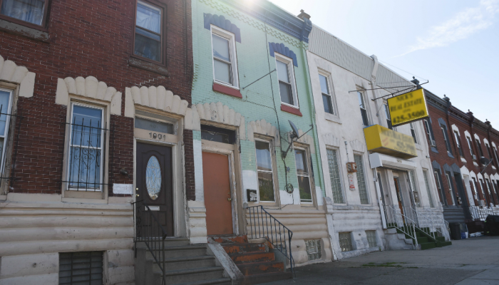 The sun sets behind a set of row homes in the Kensington neighborhood of Philadelphia