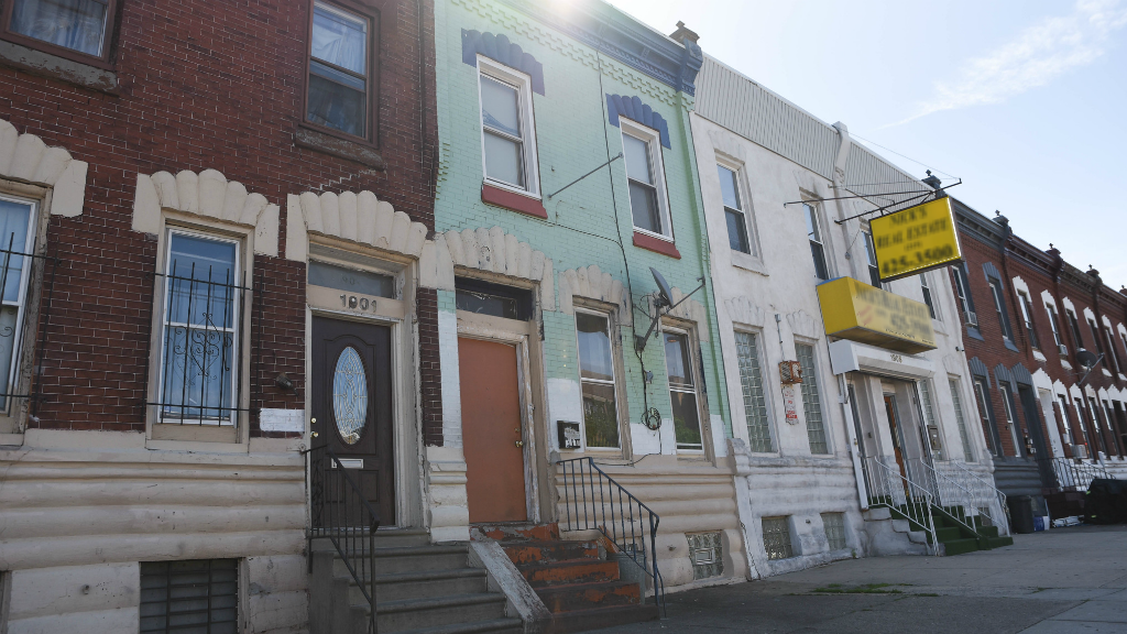 The sun sets behind a set of row homes in the Kensington neighborhood of Philadelphia