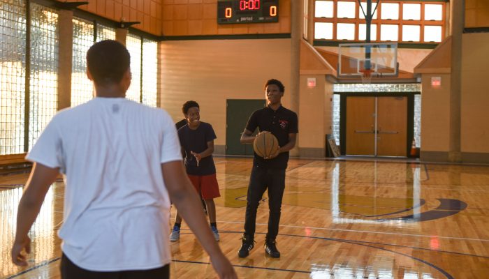 Three teenagers playing basketball in a gym