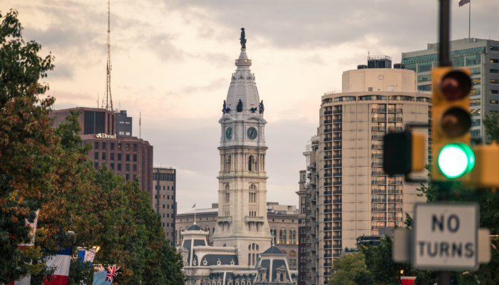 Philadelphia City Hall stands in the background among other Center City buildings and a traffic signal.
