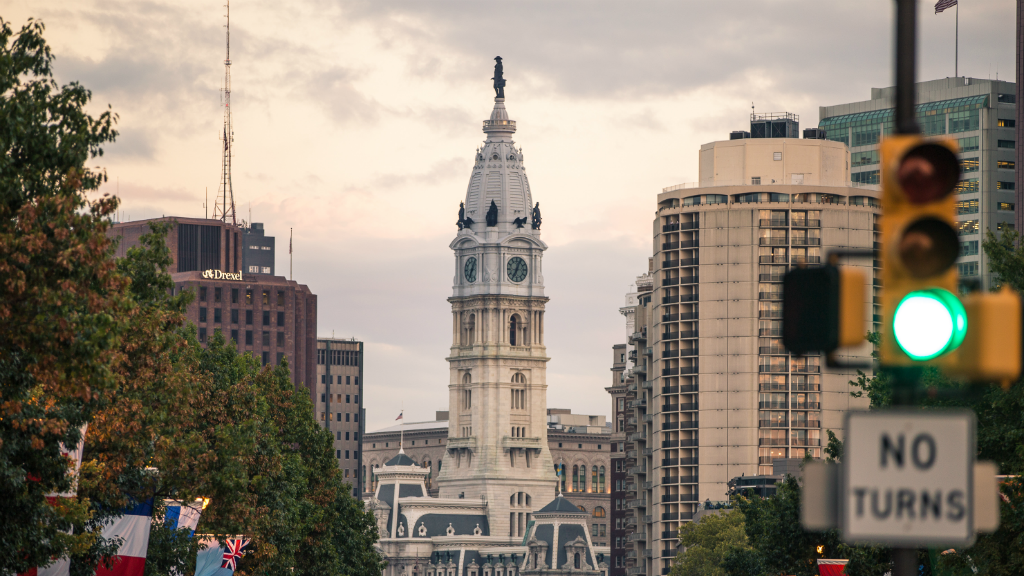Philadelphia City Hall stands in the background among other Center City buildings and a traffic signal.