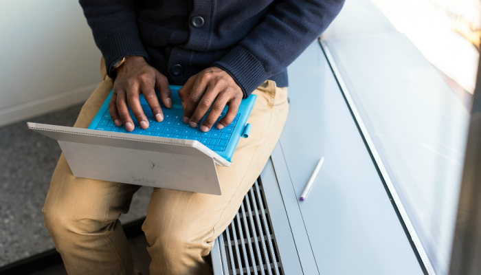 A man sits near a window as he works on his laptop