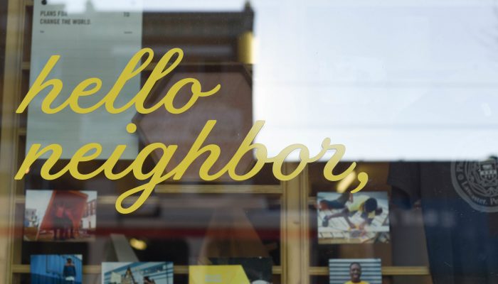 Lettering that reads "hello neighbor" on a glass door.