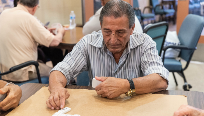 Un hombre juega dominó en un centro para los adultos mayores