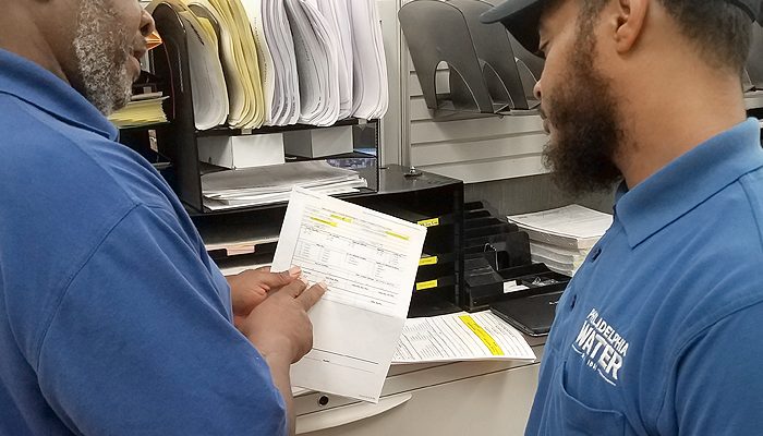 Two Water Department employees look at paperwork.