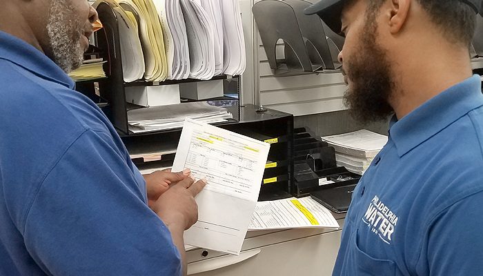 Dois funcionários do Departamento de Água examinam a papelada.