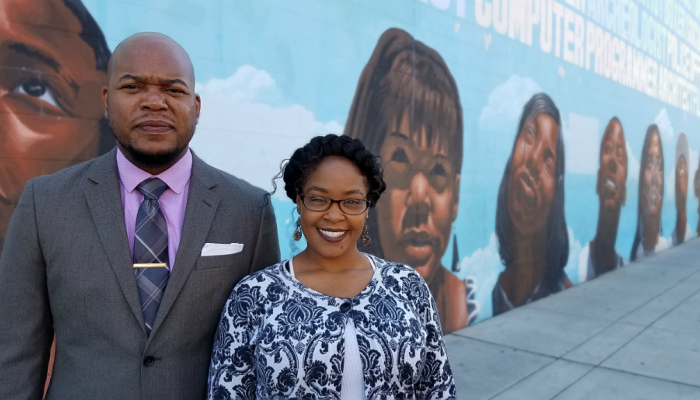 Sulaiman Wood and Chole McNeil pose for a photograph in front of a mural outside the North Philadelphia Municipal Services Center