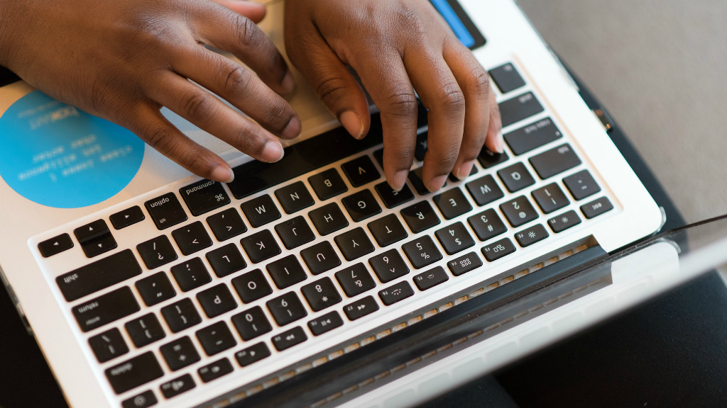 A woman types at her laptop computer.