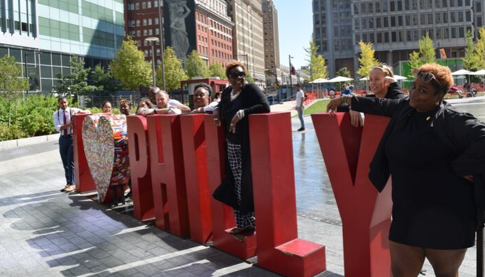 Philadelphia Community School coordinators gathering and smiling near the I love Philly sculpture in LOVE Park.