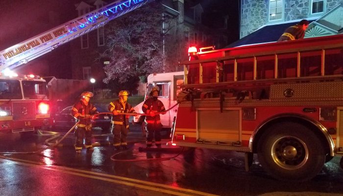 firefighters at night putting hose back on fire engine