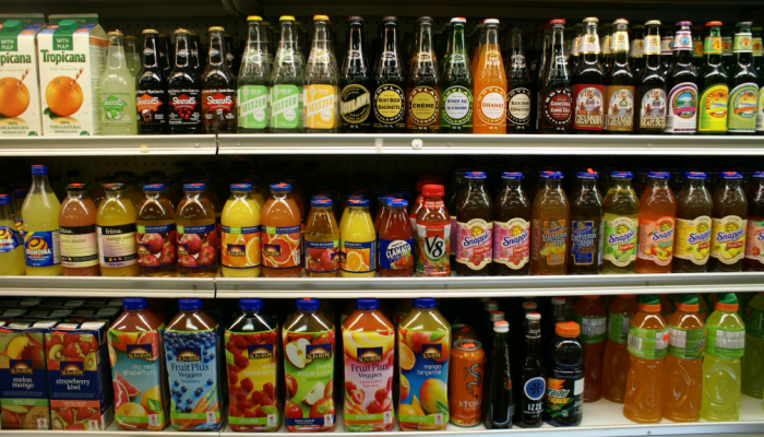 Bottled beverages of different kinds line a grocery store shelf