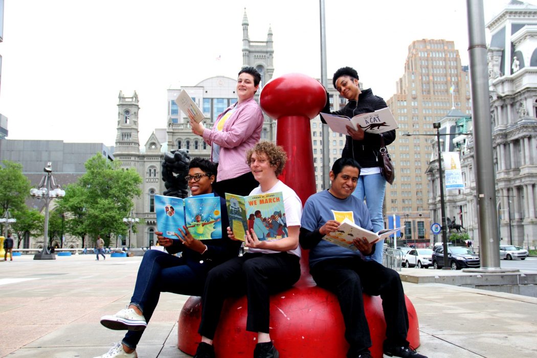 The Philly Reading Coaches team sits together outside reading books and smiling.