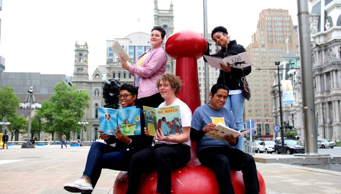 The Philly Reading Coaches team sits together outside reading books and smiling.