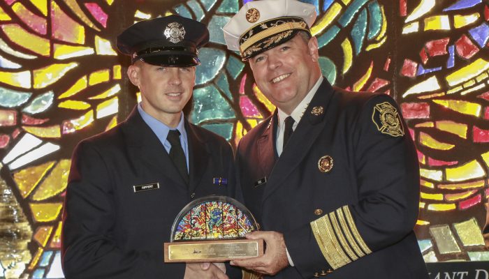 firefighters in dress uniforms shaking hands with trophy