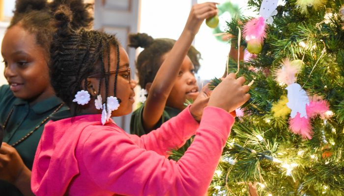 child decorating Christmas tree.