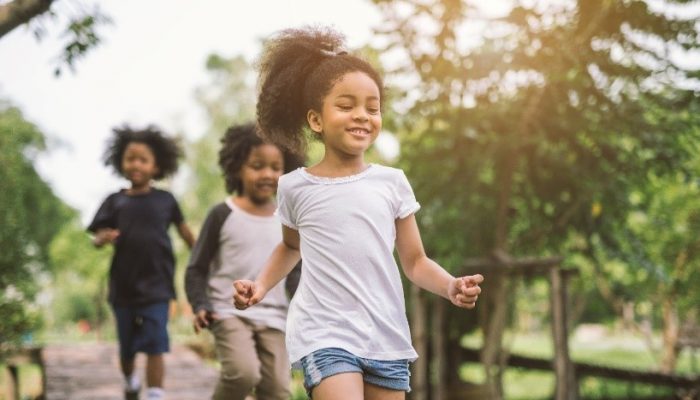 Three girls run across a footbridge.