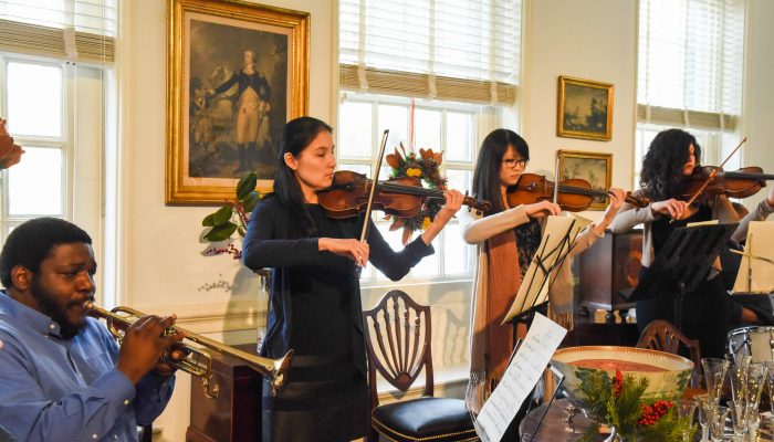 Music group playing trumpet and violin in historic house.