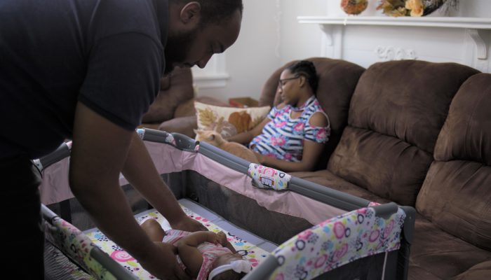 father putting a baby to sleep safely