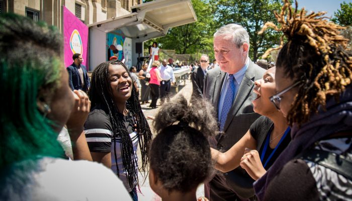 mayor kenney surrounded by students laughing and smiling on a sunny day
