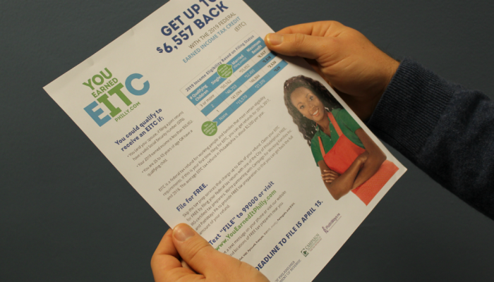 A resident of Philadelphia holds a 2019 EITC flyer in both hands