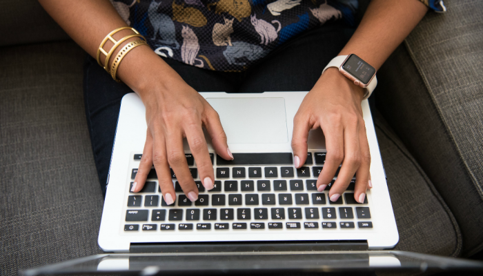 A woman keys in words on a laptop