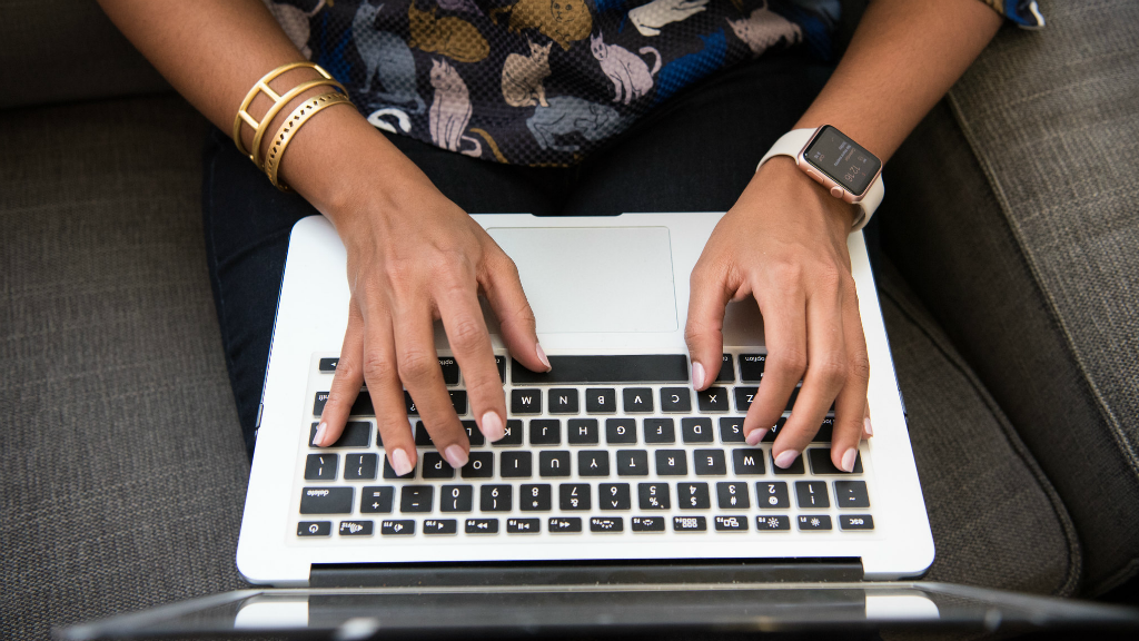 A woman keys in words on a laptop