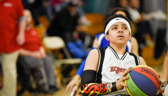 A basketball player in a wheelchair prepares to take a shot