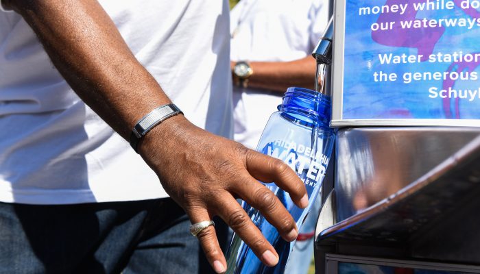 a person filling up a water bottle at a tap water station