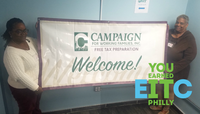 Two women hold up a "welcome" banner at a free tax preparation site in Center City, Philadelphia