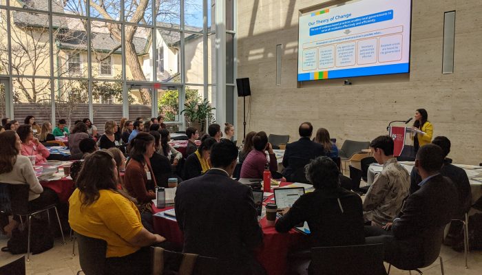 participants at the govlab conference sitting around a table, listening to the speaker