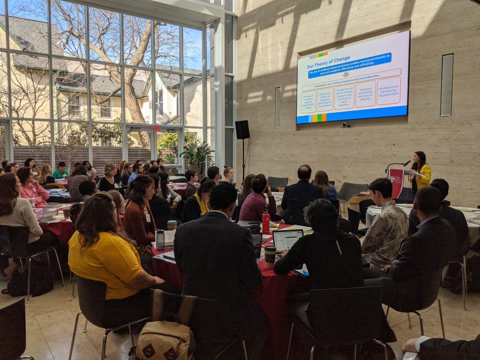 participants at the govlab conference sitting around a table, listening to the speaker