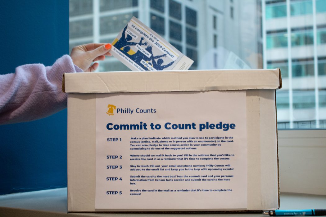 Person placing a completed Commit to Count card into a white collection box labelled "Commit to Count pledge".
