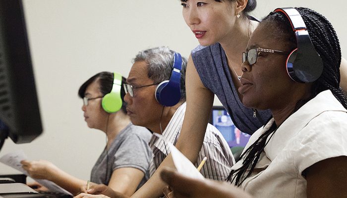 A woman helps people using computers.