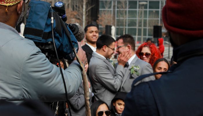 A cameraman watches as newlyweds kiss