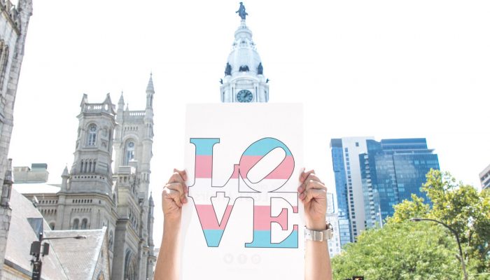 Poster spelling out "LOVE" in the colors of a transgender pride flag.