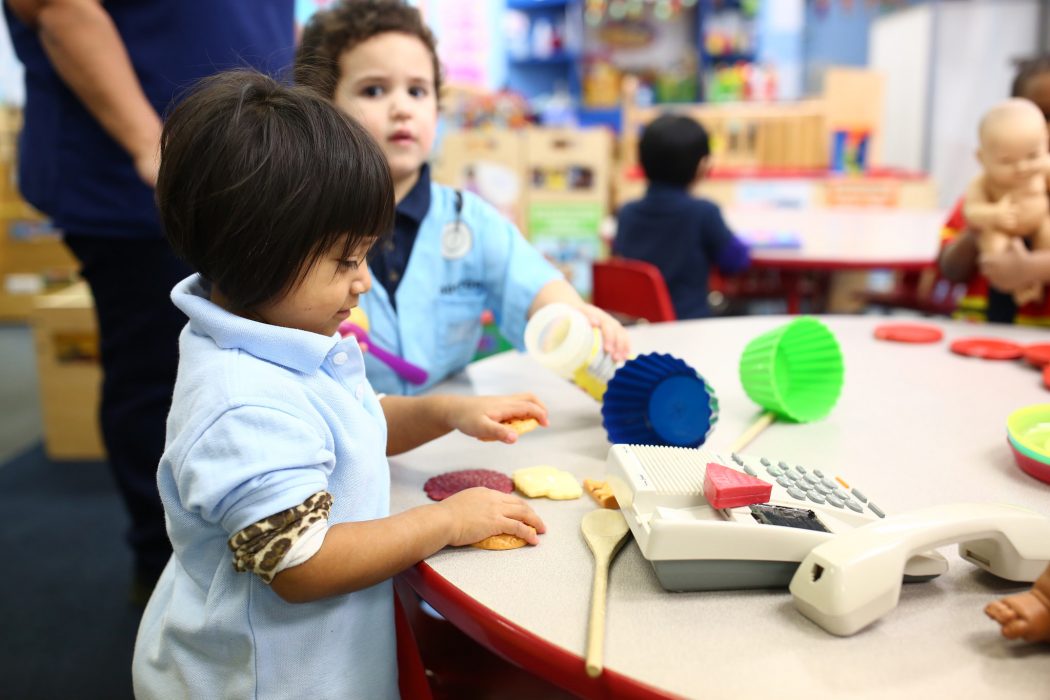 young learner plays with plastic food props in a pre-K classroom
