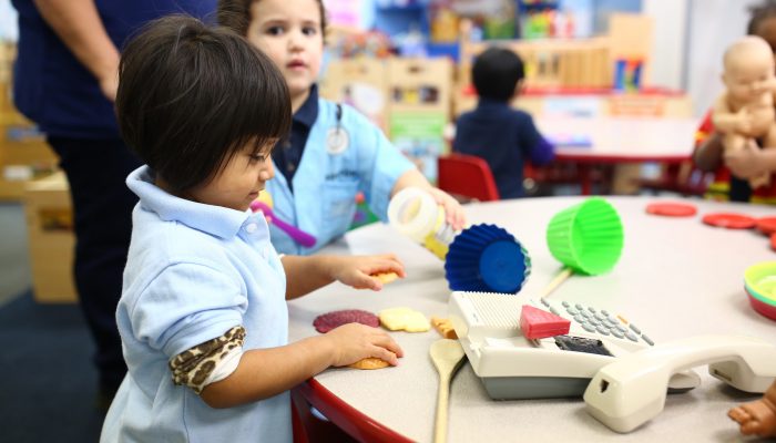 young learner plays with plastic food props in a pre-K classroom