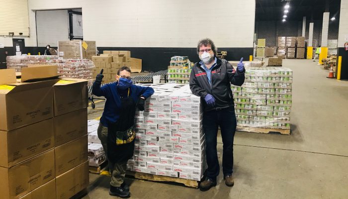 People in warehouse with boxes of food.