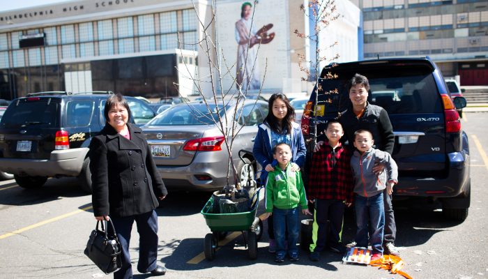 A family poses at their car with their new tree.