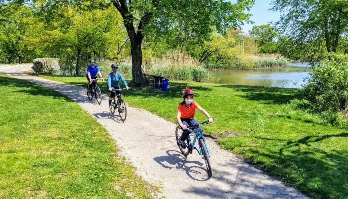 A family riding bicycles while wearing face masks.