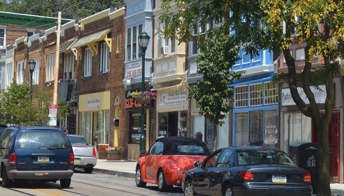 Cars drive past shops on Germantown Avenue.