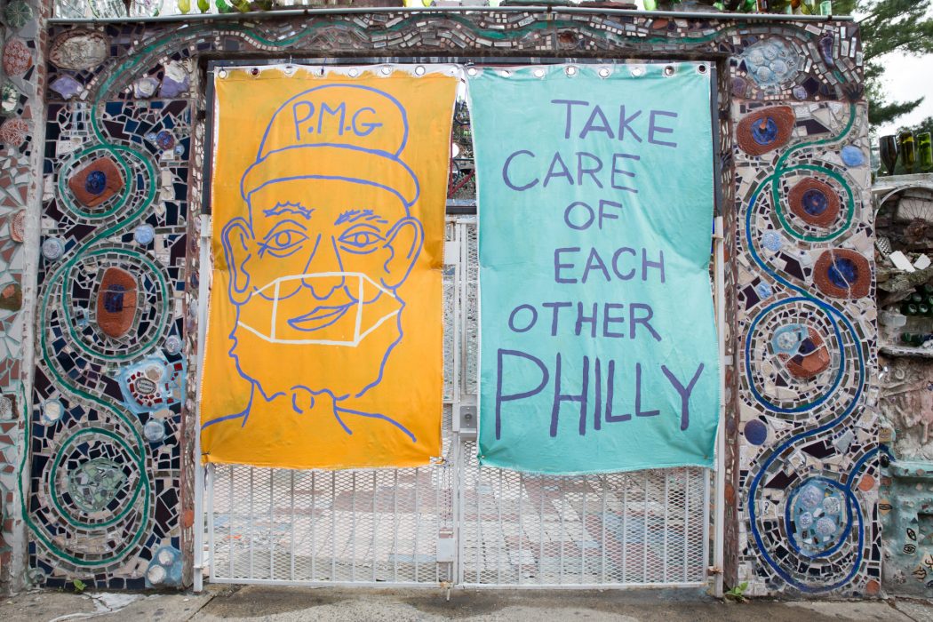 Large posters on mosaic wall. One shows outline of a person and the other says "Take care of each other Philly"