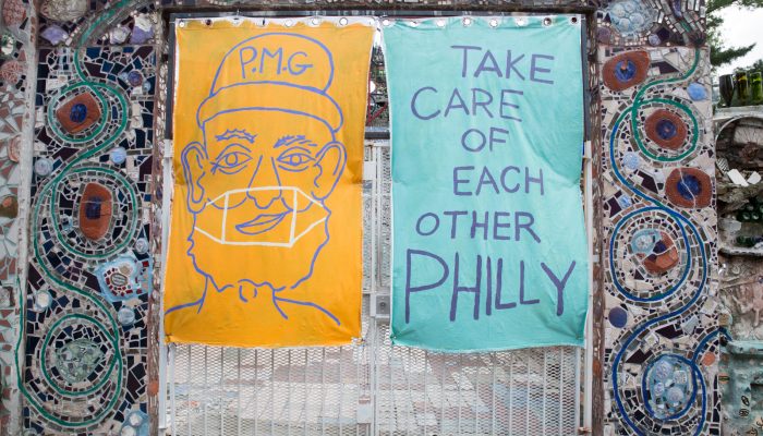 Large posters on mosaic wall. One shows outline of a person and the other says "Take care of each other Philly"