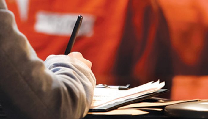 A person writes on a clipboard.